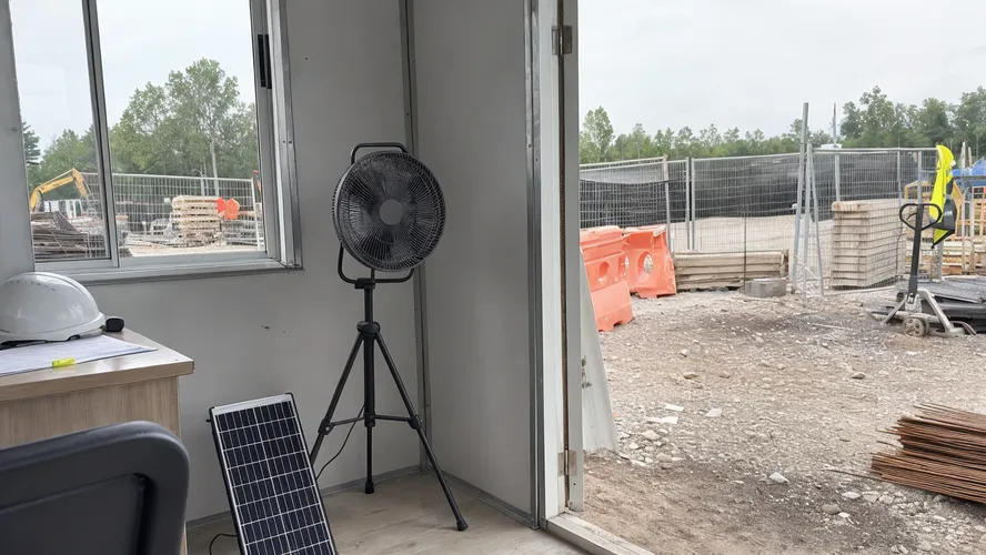Portable solar fan deployed at a temporary guard booth or construction site office without grid access