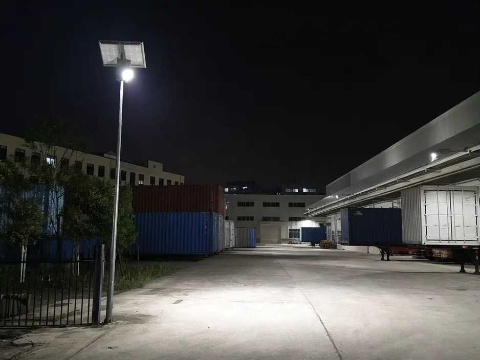 Commercial solar flood light installed on industrial site pole at night, illuminating a logistics yard