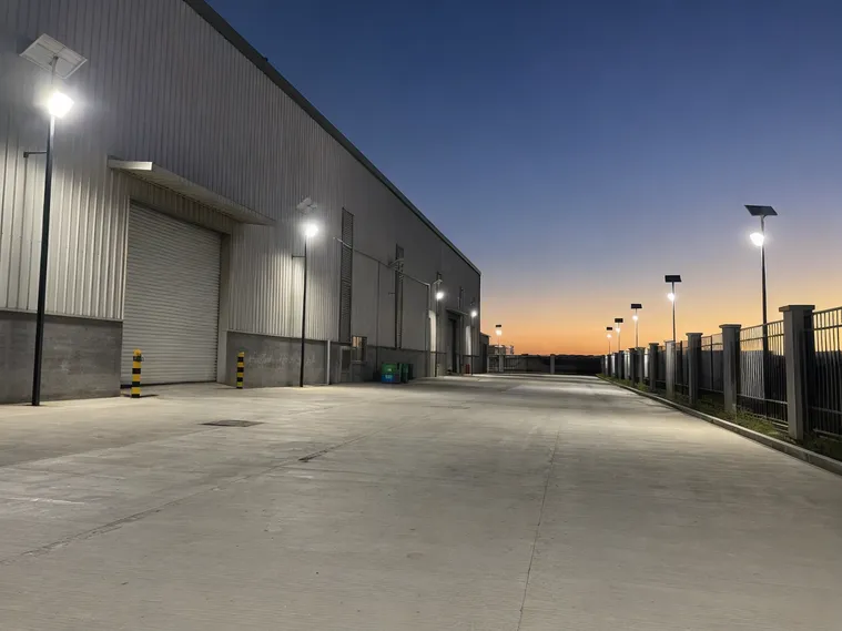 Solar flood lighting deployed across commercial warehouse perimeter at dusk