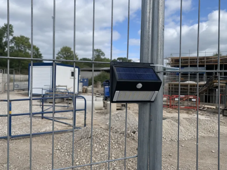 Solar motion sensor light deployed on a temporary construction site fence