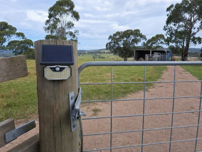 Solar motion sensor light mounted on a rural farm gate for off-grid perimeter security