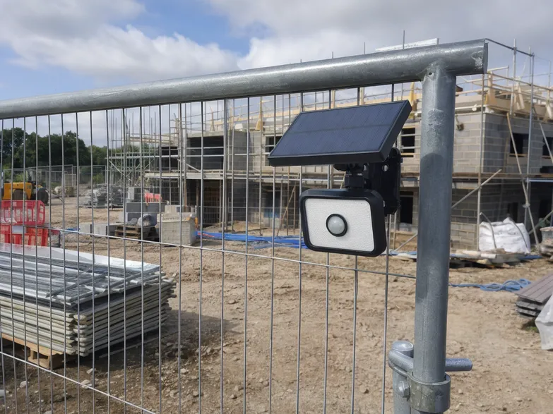 PIR solar security light mounted on temporary construction site fencing