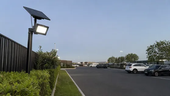 Solar motion sensor flood light mounted at a commercial parking lot perimeter