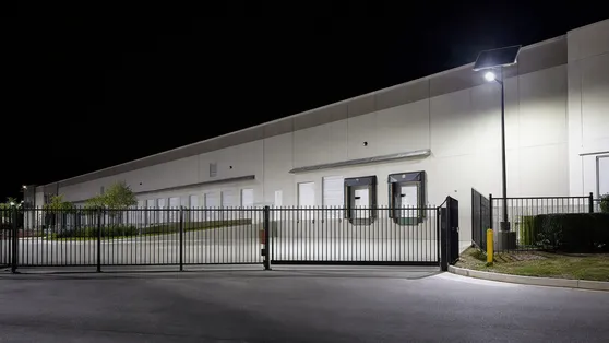 Solar motion sensor flood light illuminating a warehouse loading dock perimeter at night