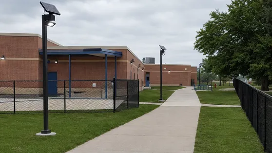 Solar security lights along school campus pathway and building perimeter