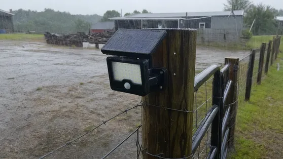 Solar security light on a rural farm perimeter fence in heavy rainfall conditions
