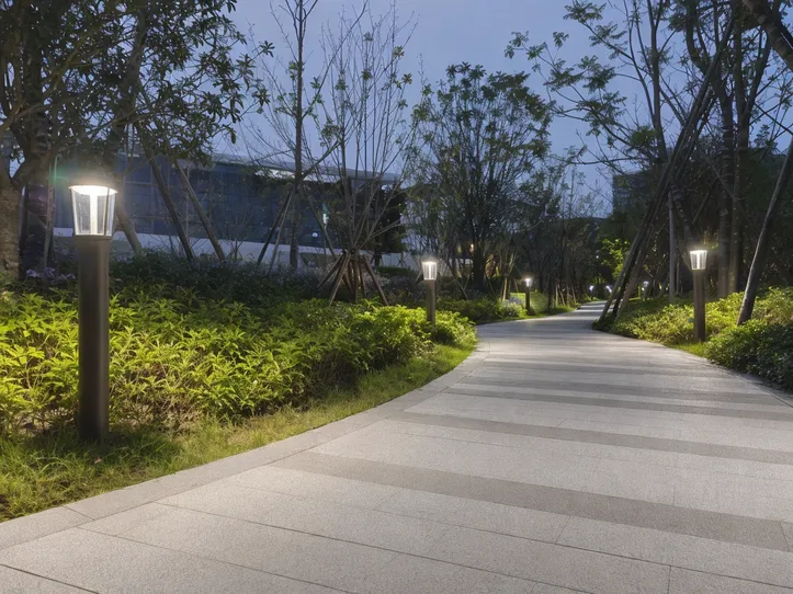 Solar landscape lighting fixtures illuminating a public park pathway and garden beds