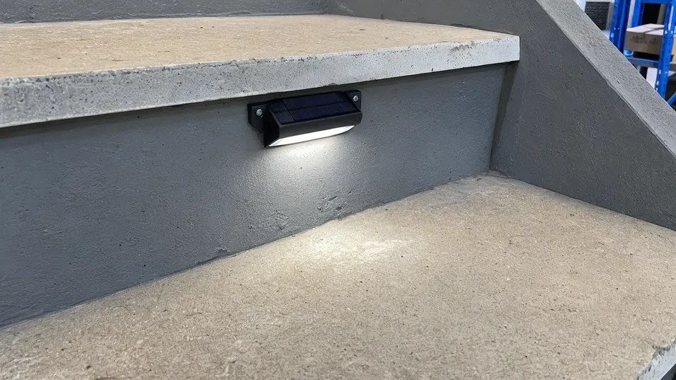 Solar deck light positioned on stair riser illuminating tread without glare at descending eye level