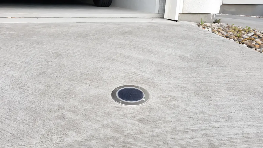 Solar paver light embedded flush into concrete driveway surface, designed for foot and light vehicle traffic