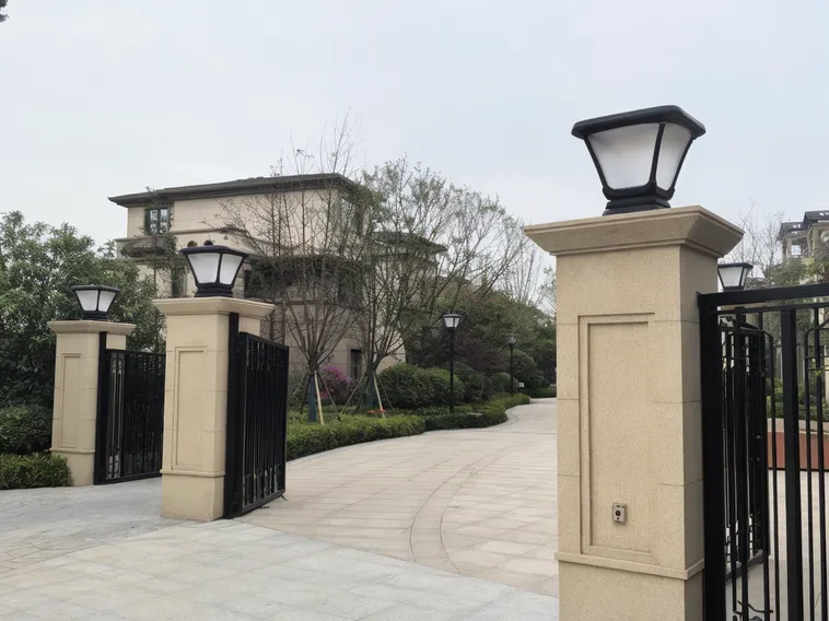 Solar post top lights at a residential community entrance gate with consistent finish across multiple fixtures