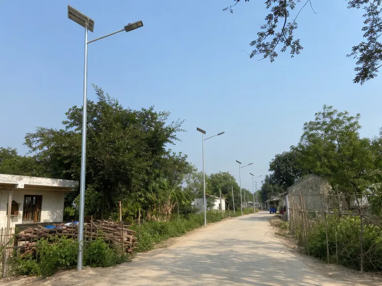 Direct burial solar street lighting poles installed along a rural village access road in an off-grid setting