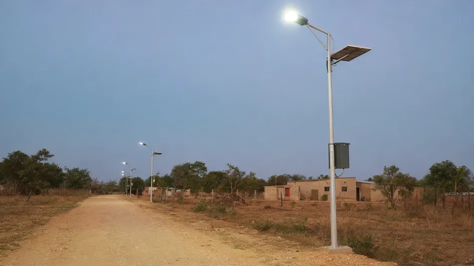 Split solar street lights illuminating a rural off-grid road in Africa with separate battery box mounted at serviceable height on the pole
