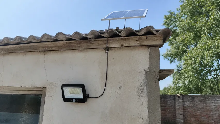 Solar wall light with separate panel mounted on a shaded north-facing wall, cable running to roof-mounted panel