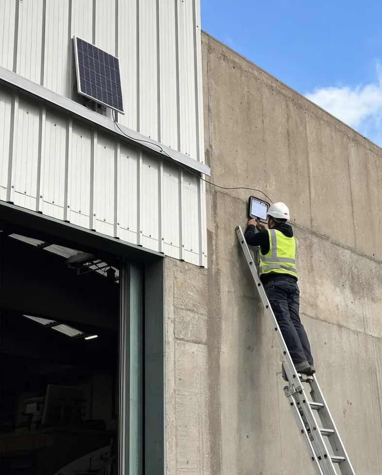 Building retrofit contractor installing separate-panel solar wall lights on mixed-orientation warehouse walls