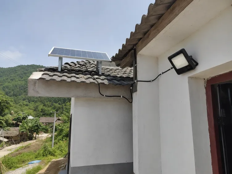 Separate-panel solar wall light installed on a rural community building with the panel mounted on an adjacent rooftop for maximum sun exposure