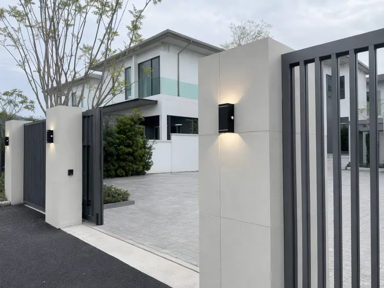 Uniform up-down solar wall lights installed across a gated community entrance with consistent facade illumination